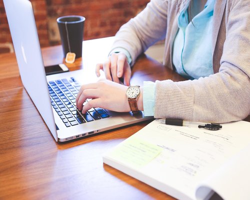 A professional woman stretching her arms gently during a break at her modern workspace