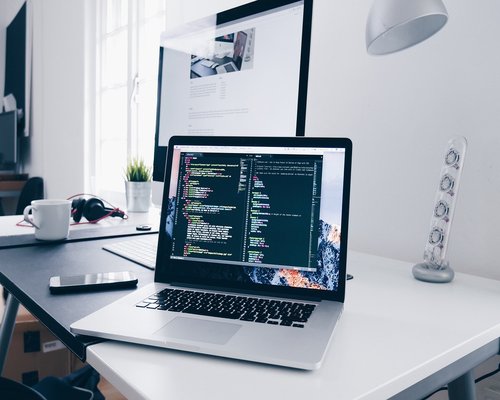 A well-lit ergonomic home office setup with comfortable chair and elevated monitor